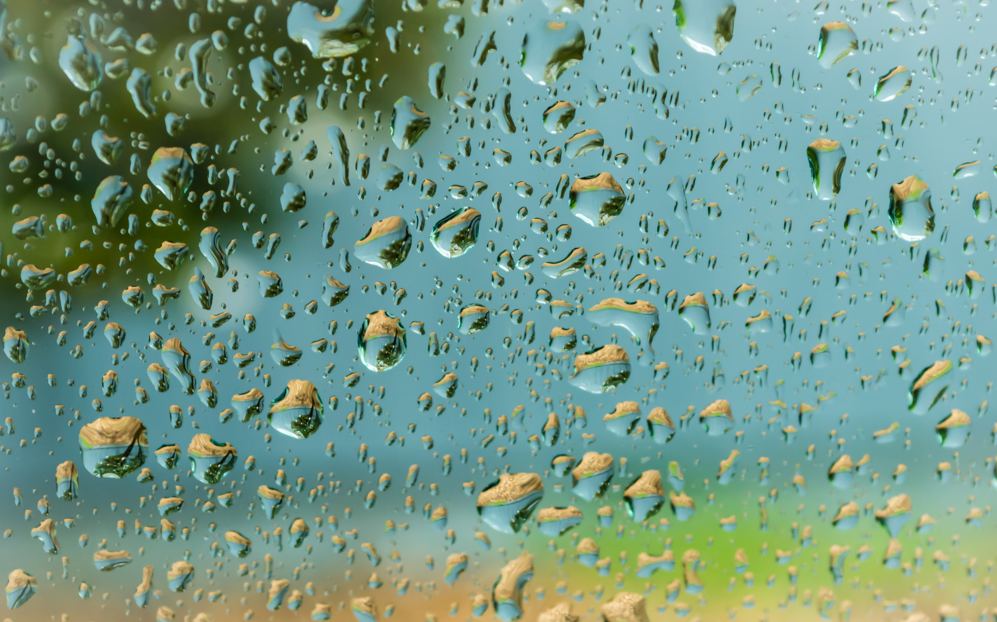 Сверху капает вода. Капли на стекле. Капли воды на стекле. Капли дождя. Дождь на стекле.