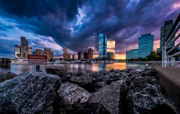 Picture the sky, sunset, the city, river, stones, shore, skyscrapers, boats