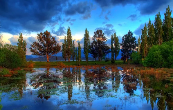 The sky, clouds, trees, mountains, pond, reflection