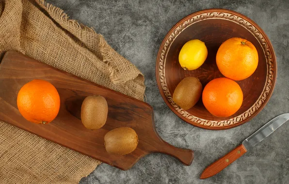 Lemon, oranges, kiwi, plate, knife, fruit, grey background, burlap