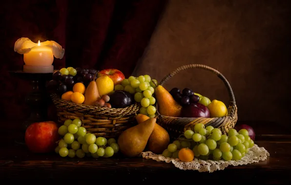 The dark background, table, apples, candle, grapes, fabric, fruit, nuts