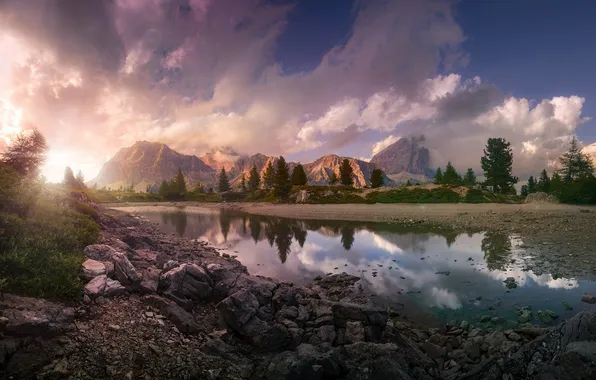 The sky, water, the sun, clouds, trees, mountains, reflection, stones