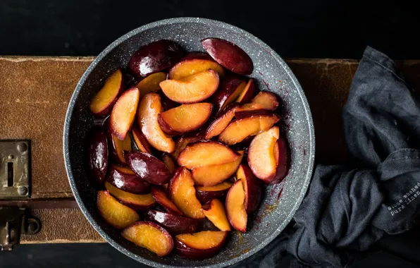 The dark background, fabric, suitcase, peaches, slices, pan, chopped