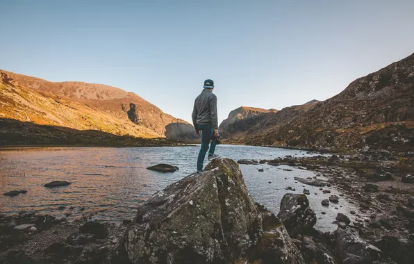 The sky, the sun, lake, hills, hat, stone, back, jeans