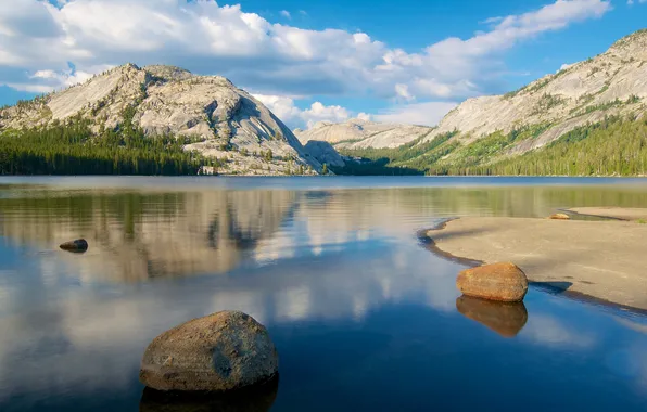 The sky, clouds, trees, mountains, lake, stones