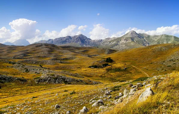 The sky, grass, clouds, mountains, stones