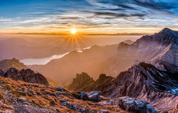 The sky, the sun, clouds, rays, mountains, river, stones, rocks