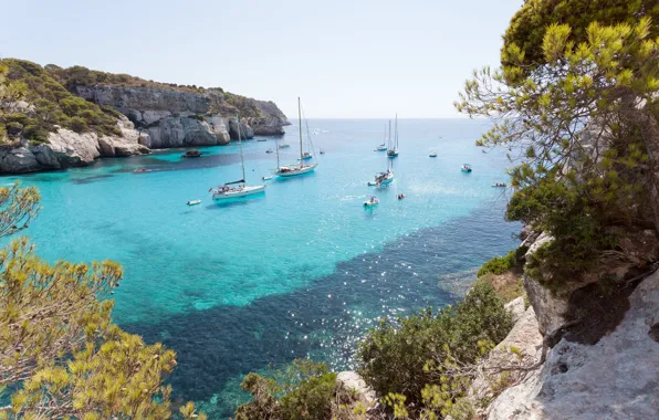 Ocean, rocks, sailboat, crystal clear water