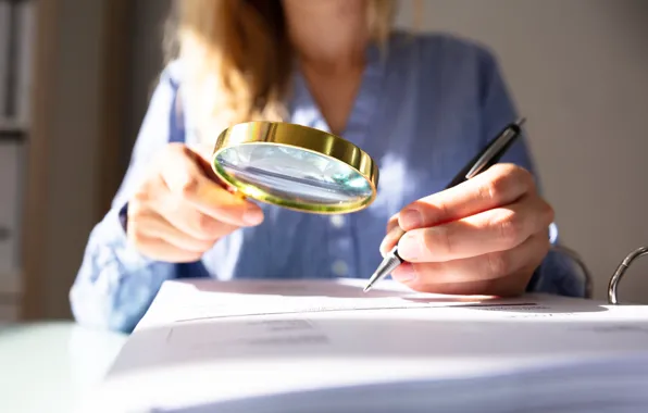 Woman, paper, magnifying glass