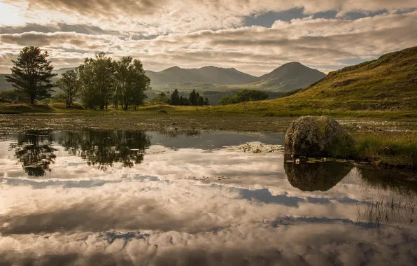 The sky, clouds, trees, mountains, lake, stones
