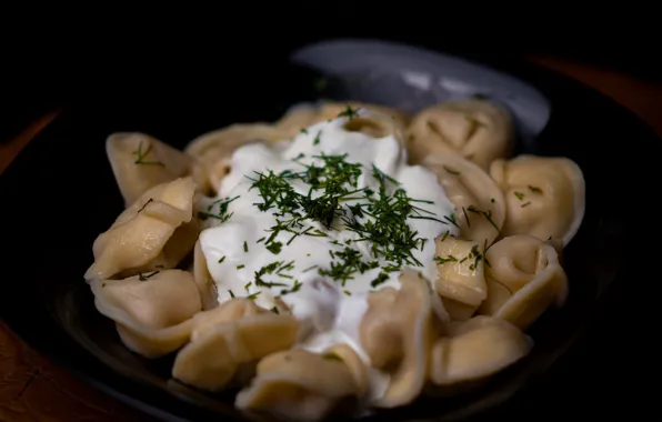 Greens, table, dill, sour cream, dumplings, black plate, meat dumplings with sour cream and herbs