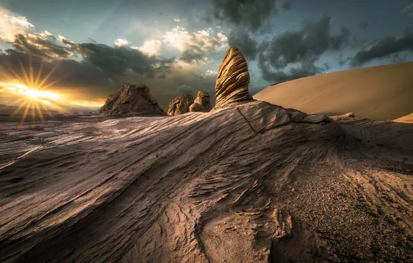 The sky, the sun, clouds, rays, stones, rocks, desert, slope