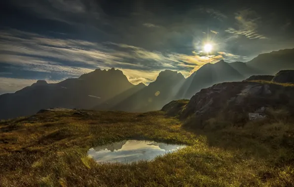 The sky, grass, water, the sun, clouds, rays, sunset, mountains