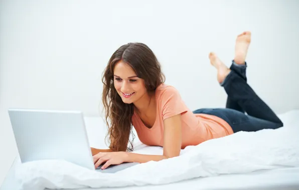 Girl, smile, jeans, bed, laptop, brown hair, t-shirt