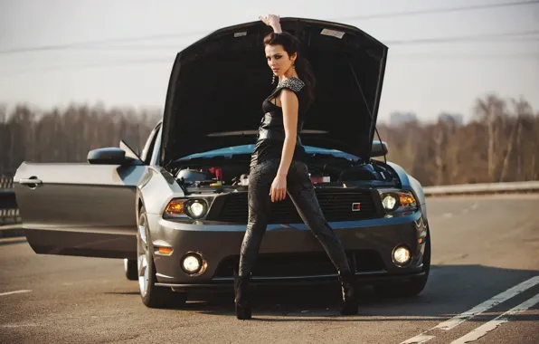 Girl, brunette, beautiful girl, looking at the camera, standing next to Ford car, opened the …