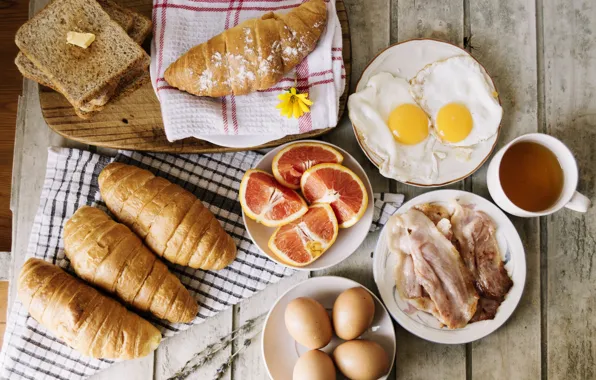 Eggs, bread, citrus, tablecloth, bacon, croissants