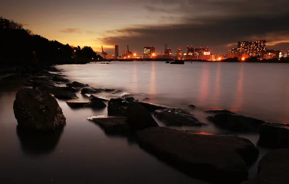 Picture sea, the city, lights, stones, the evening