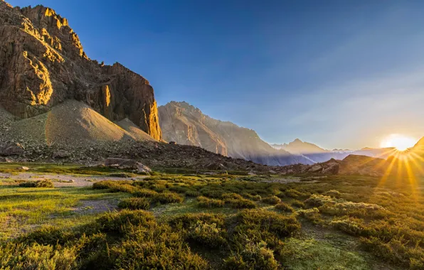 The sky, grass, the sun, rays, mountains, stones, rocks, dawn