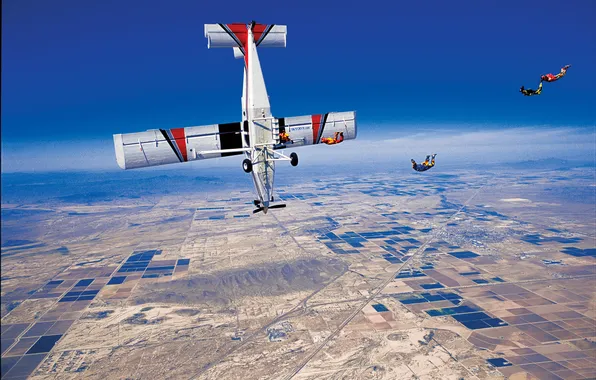 Picture the sky, the plane, road, parachute, container, village, skydivers, extreme sports