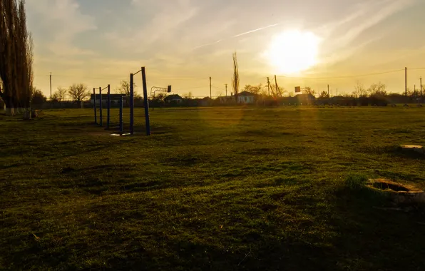 Picture the sky, the sun, clouds, trees, green grass, the fence, village, puddle
