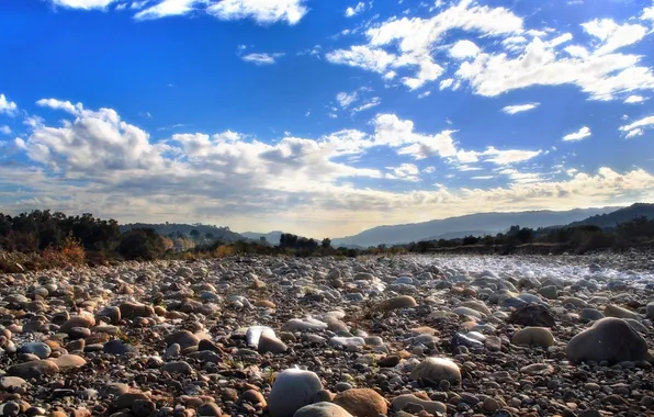 The sky, clouds, trees, river, stones