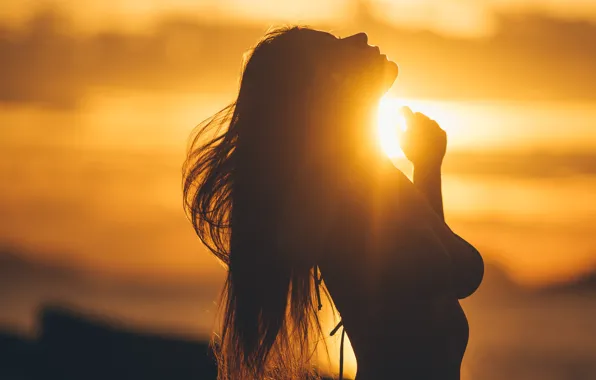 Silhouette of a girl, a ray of sunshine, sunset on the sea