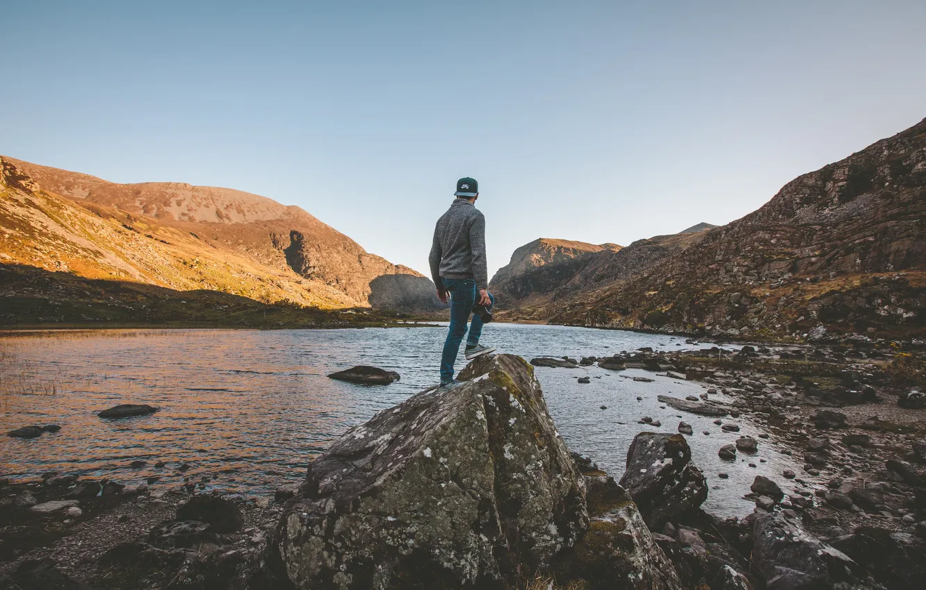 Photo wallpaper the sky, the sun, lake, stones, hills, hat, back, jeans
