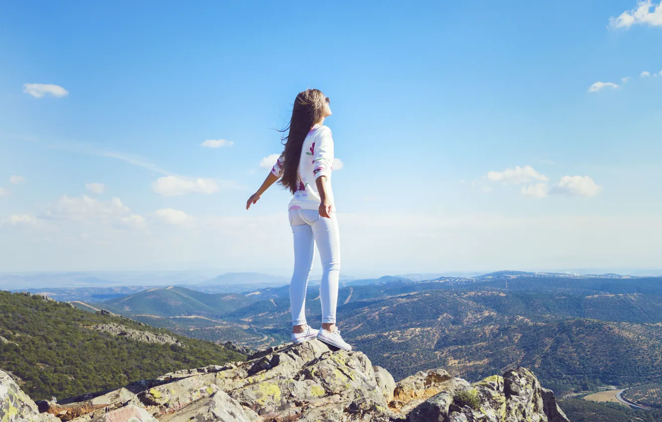 Photo wallpaper the sky, girl, clouds, pose, the wind, hair, mountain, jeans