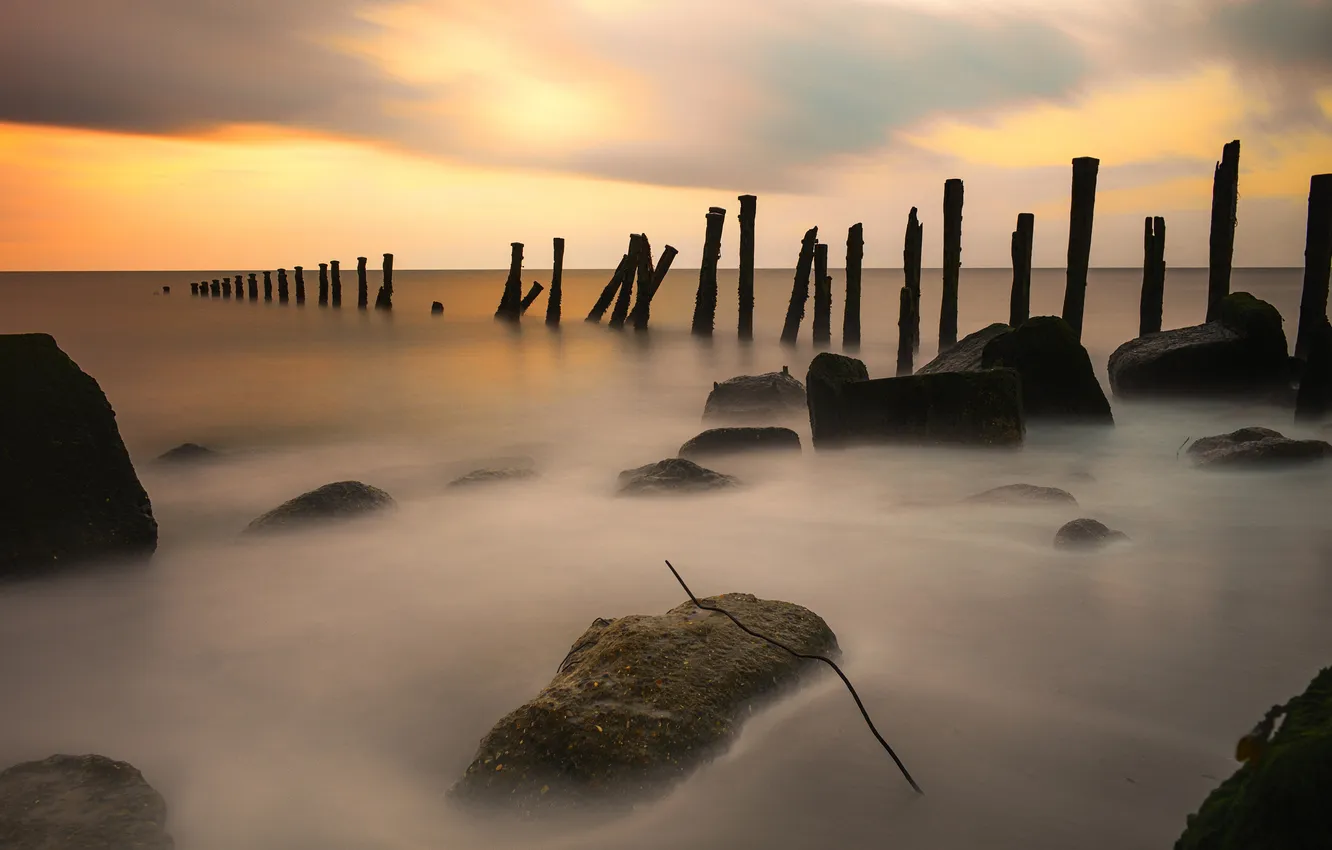 Photo wallpaper sea, stones, shore, posts, piles