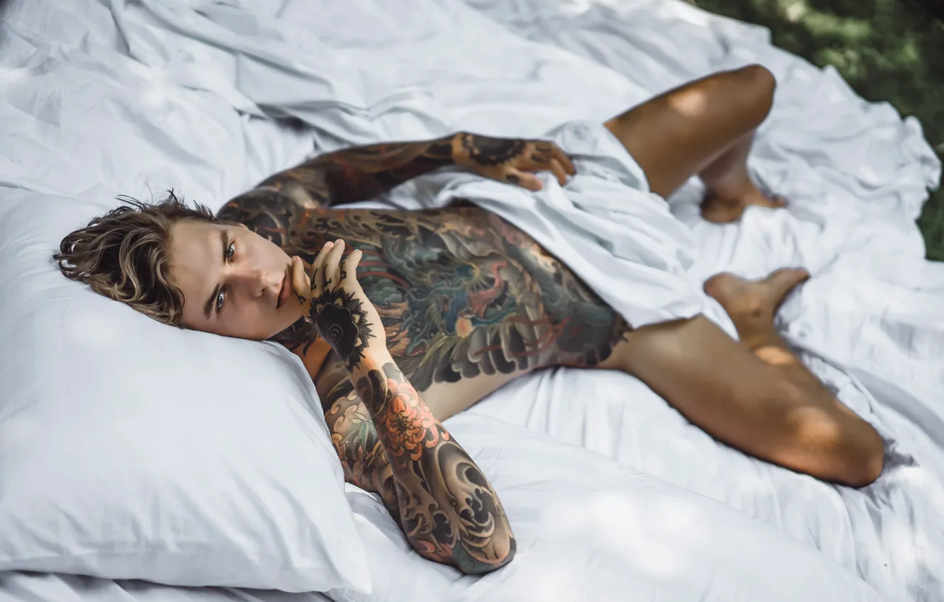 Мужчина с татуировками в постели