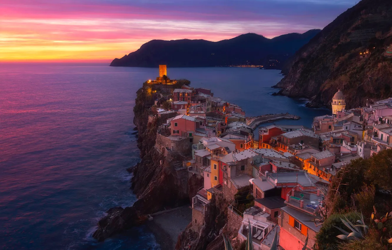 Photo wallpaper sea, sunset, mountains, the city, lights, rocks, shore, view