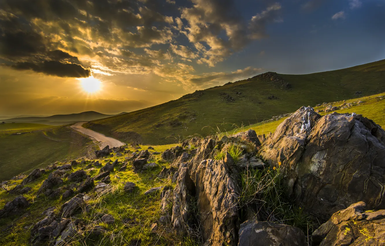 Photo wallpaper road, the sun, rays, stones, hills, morning