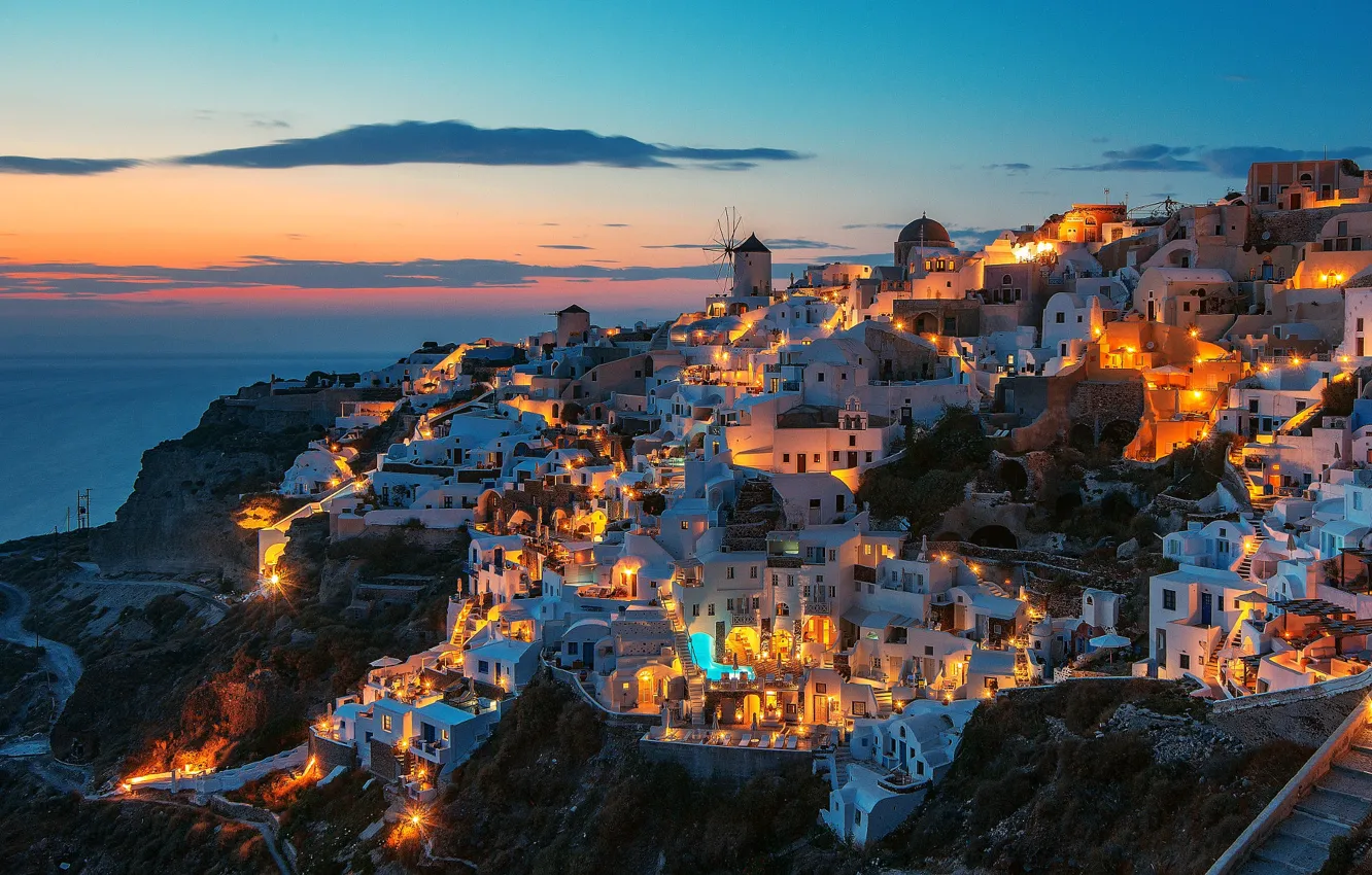 Photo wallpaper sea, clouds, sunset, night, the city, lights, rocks, shore