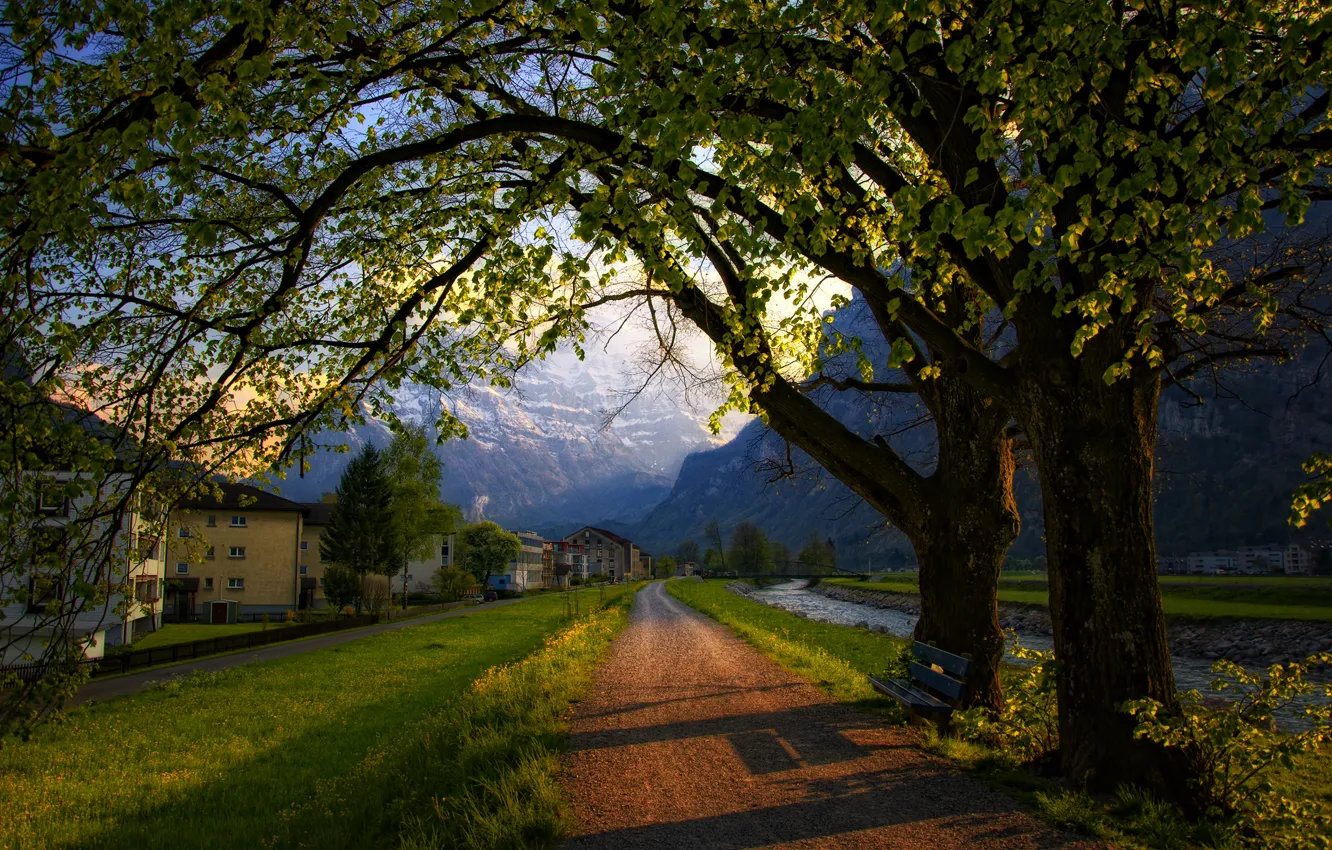 Photo wallpaper road, trees, mountains, bench, the city, home, spring, the evening