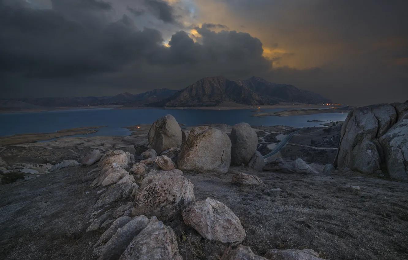 Photo wallpaper road, mountains, clouds, lights, lake, stones, twilight