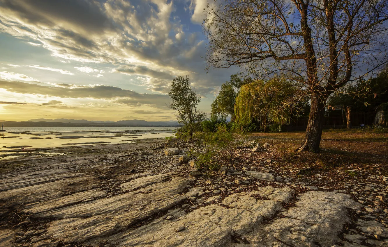 Photo wallpaper the sky, clouds, trees, sunset, lake, stones, shore, Italy