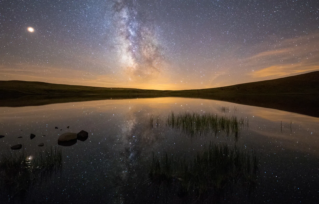 Photo wallpaper grass, stars, night, lake, reflection, stones, hills, shore