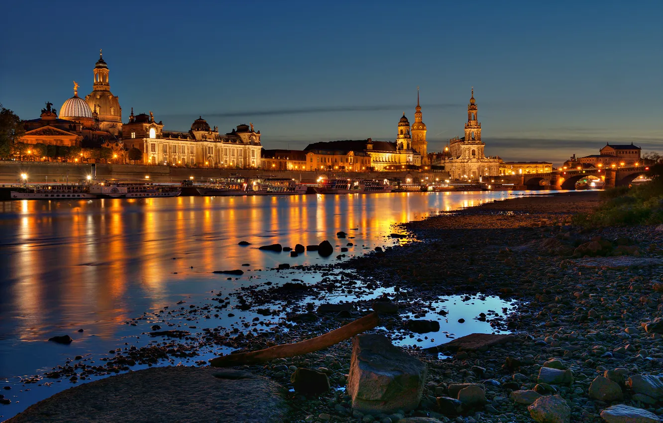 Photo wallpaper night, bridge, the city, lights, river, stones, shore, boat